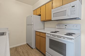 A white stove and microwave are installed above a white refrigerator in a kitchen.